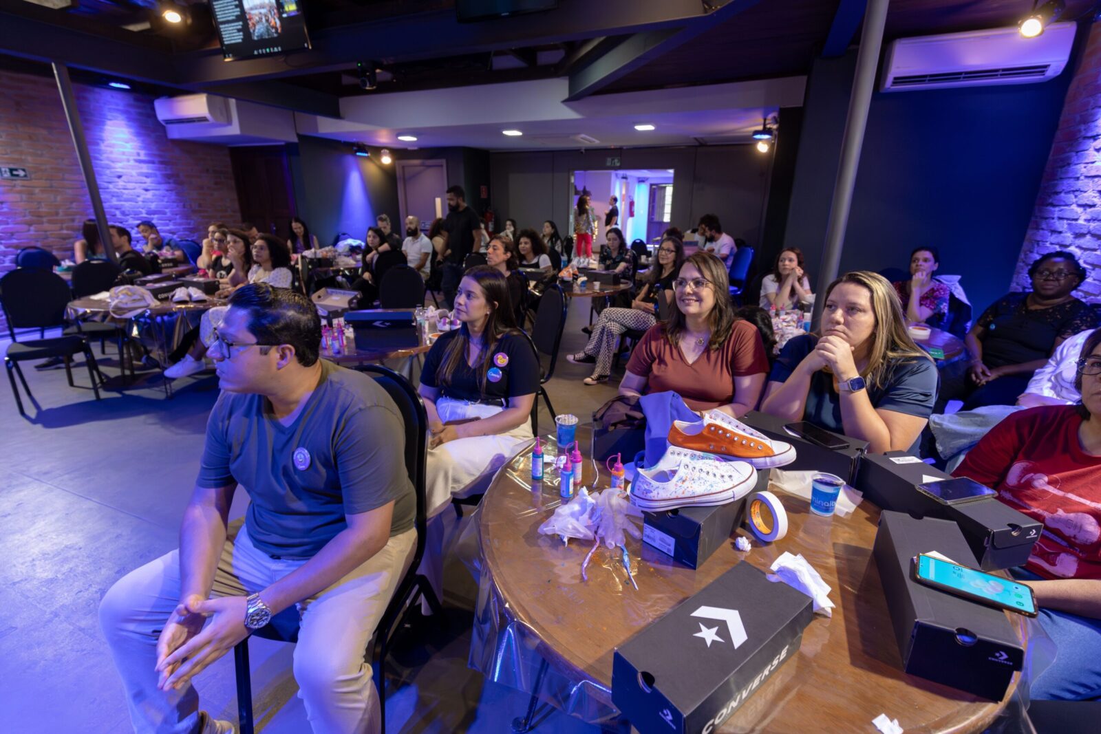 a group of people sitting at a table raising their hands